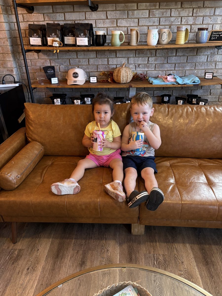 Two kids with drinks on the leather couch